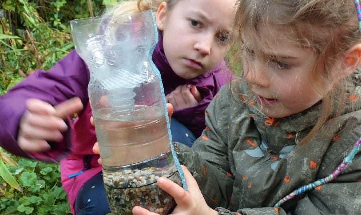 Two girls experimenting with a water bottle outside
