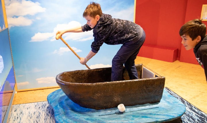 Two kids rowing a boat at the Kindermuseum