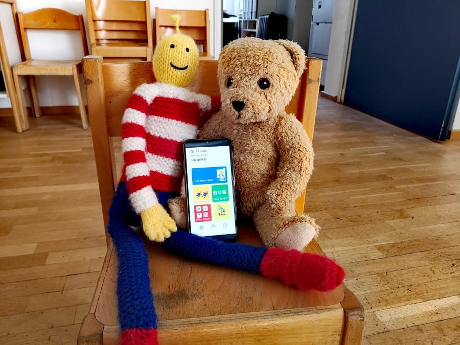 A teddy bear and a puppet looking at the Kikus mobile app